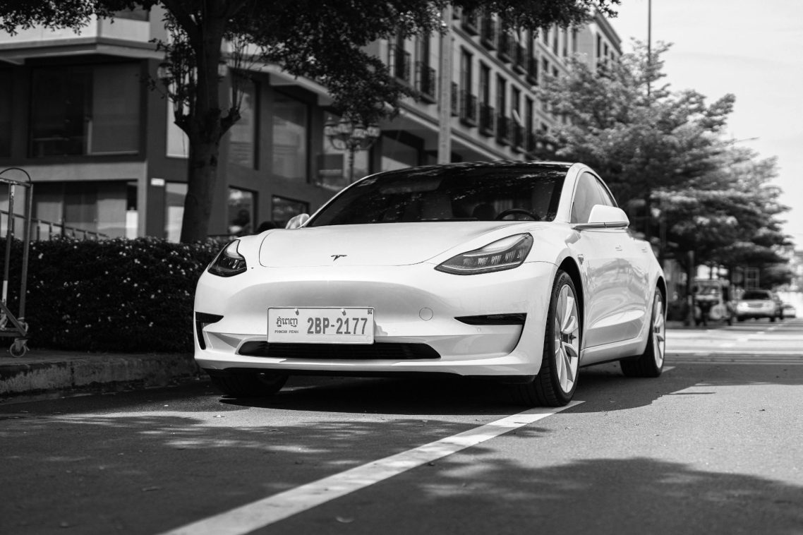 Véhicule premium electrique Voiture électrique blanche garée sur une rue bordée d'arbres.